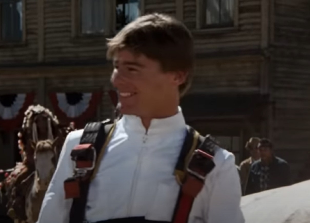 Screenshot: Jan-Michael Vincent wearing white shirt is looking at side and smiling - from Hooper (1978)