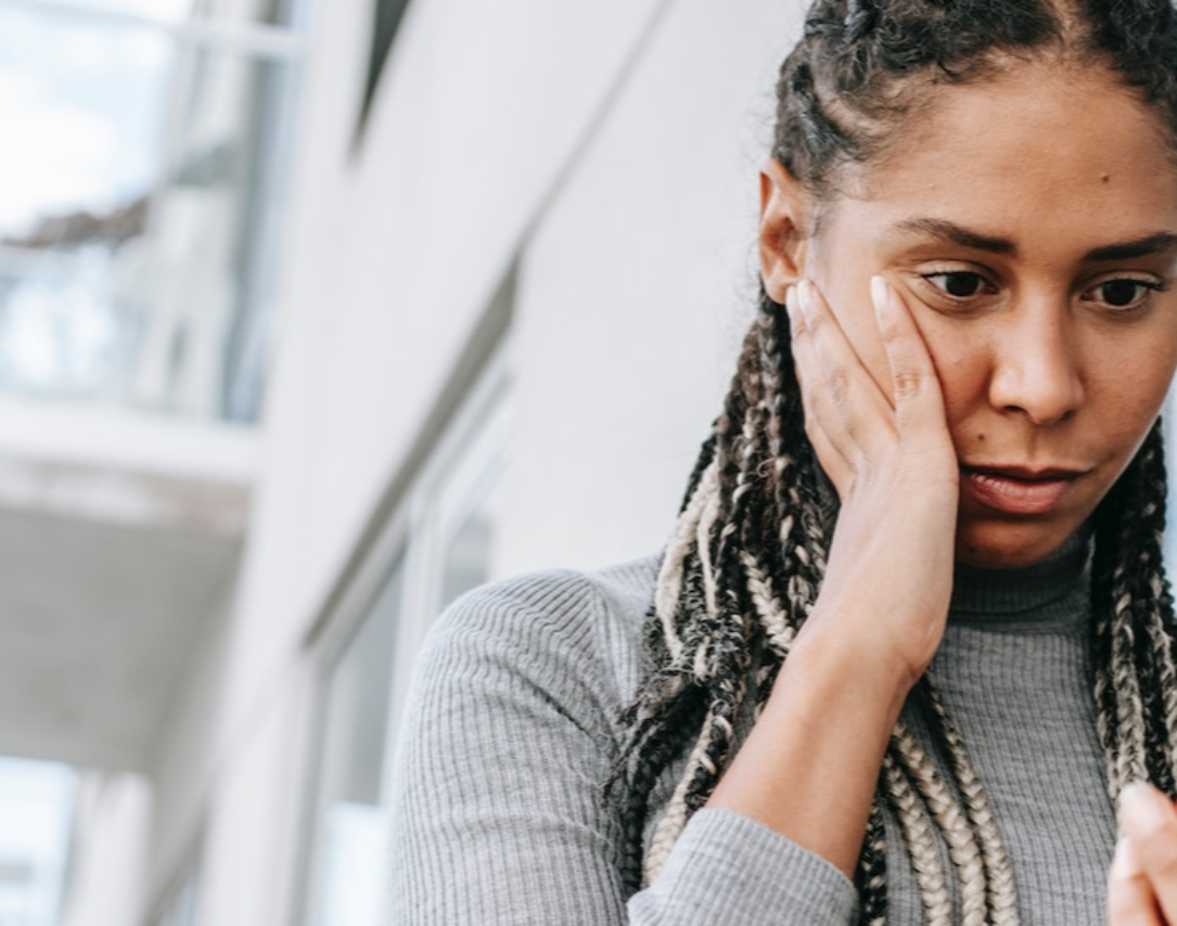 Black woman is reading message on the phone and looking shocked.