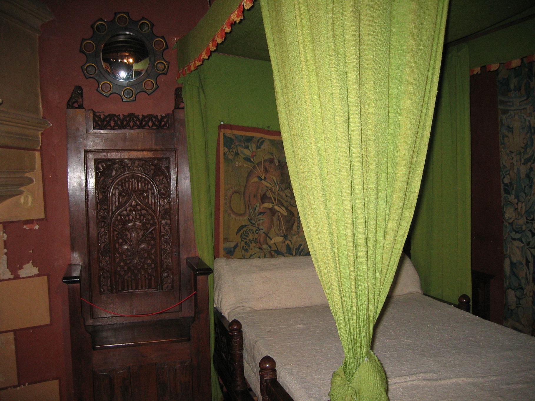 Canopy bed, carved wooden high-backed chair and mirror, bedroom at Langeais castle, France.