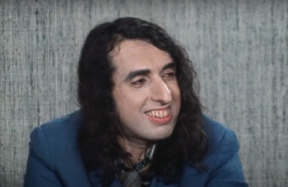 Tiny Tim sitting at a desk giving an interview