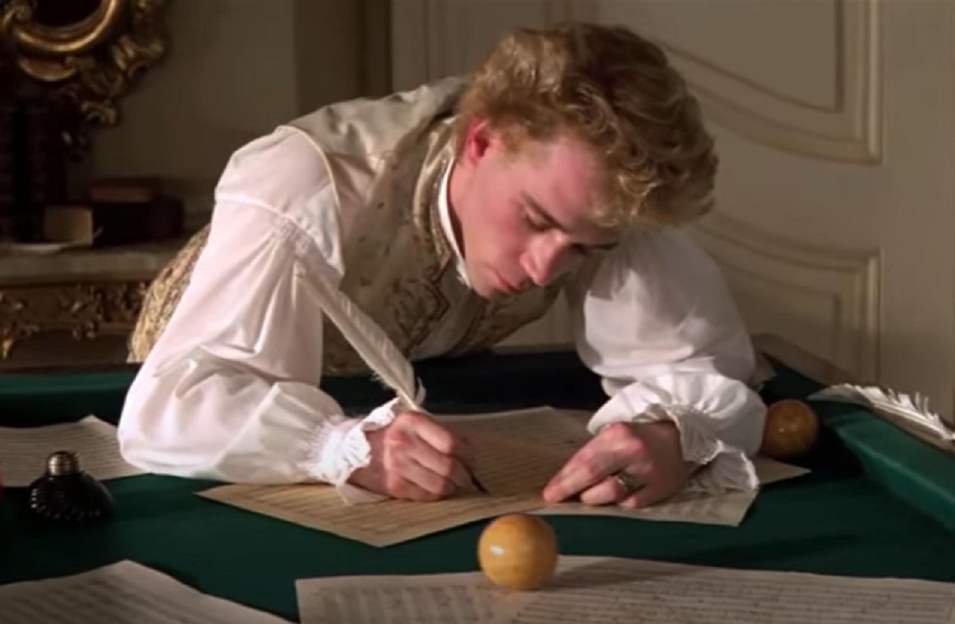 Screenshot: Wolfgang Amadeus Mozart wearing white shirt is making music - from Amadeus (1984)