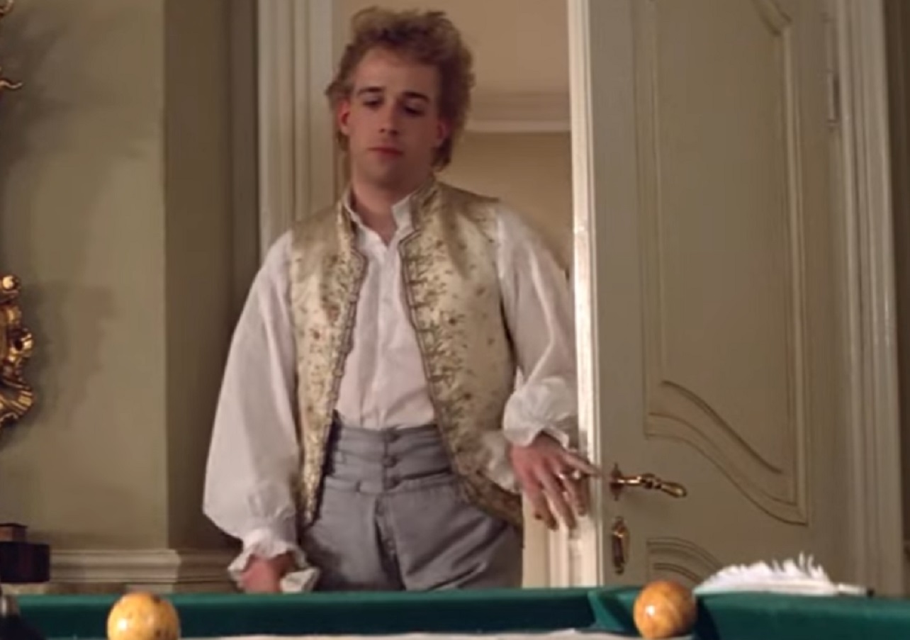 Screenshot: Wolfgang Amadeus Mozart in white shirt is entering in room with pool table - from Amadeus (1984)