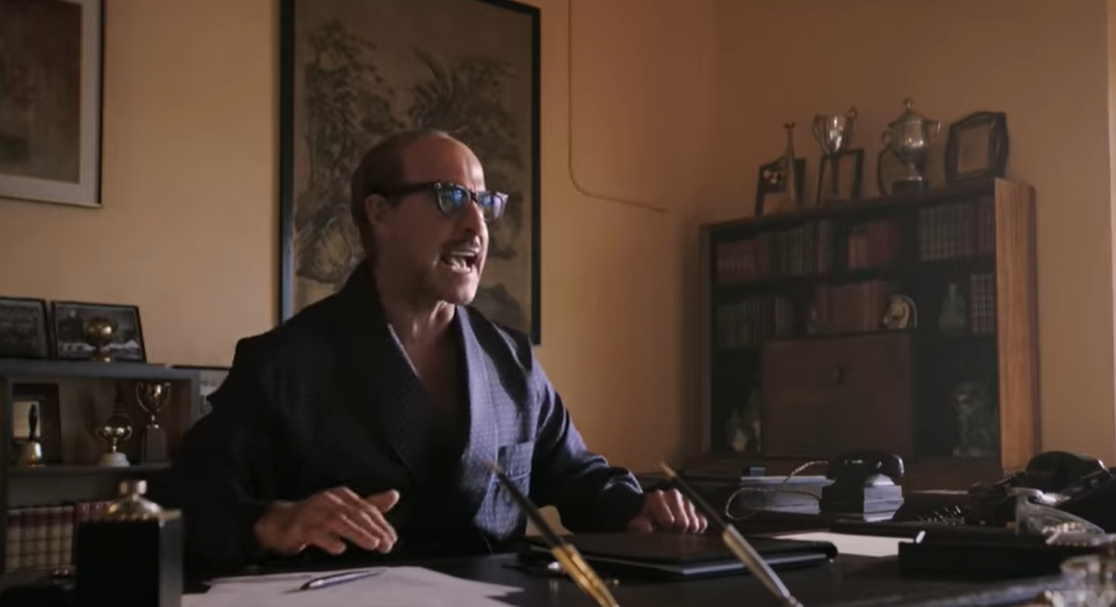 Stanley Tucci as Jack L. Warner sitting at desk