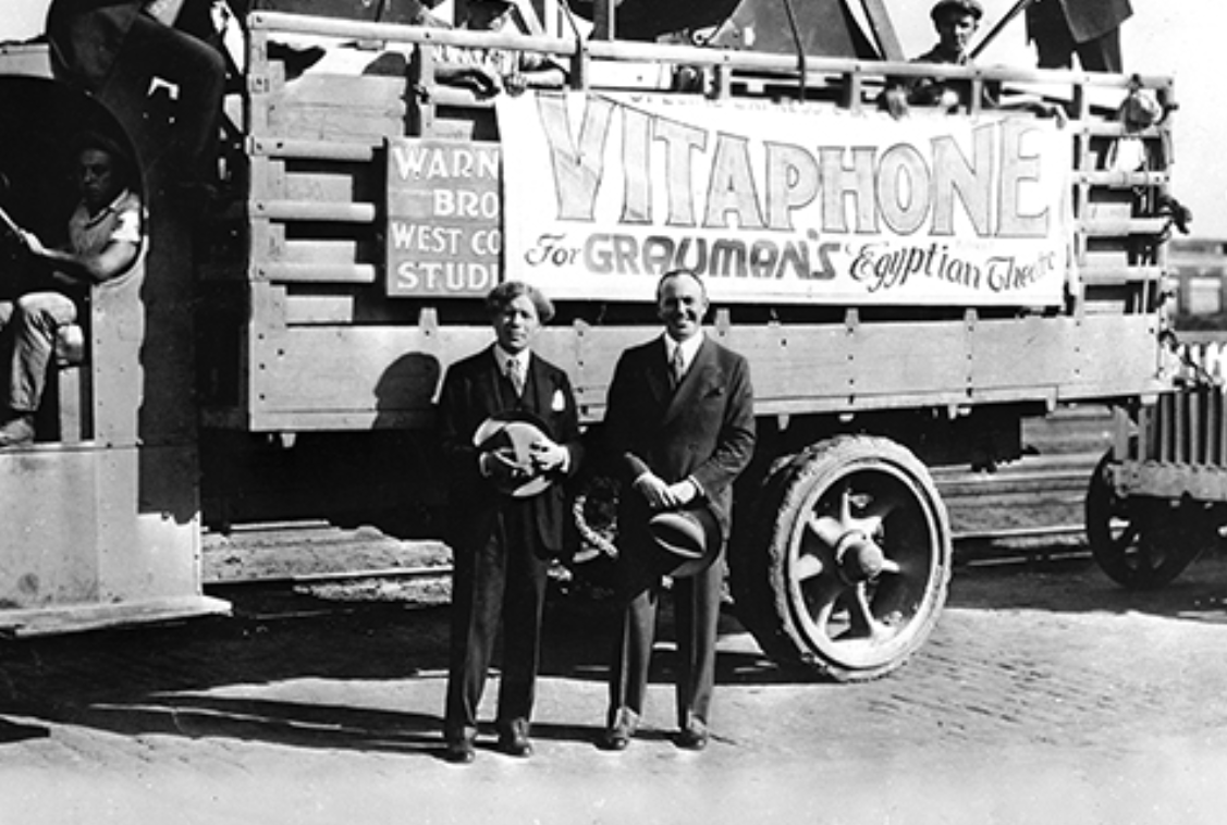 Jack L. Warner stand in front of a truck containing the first Vitaphone sound equipment