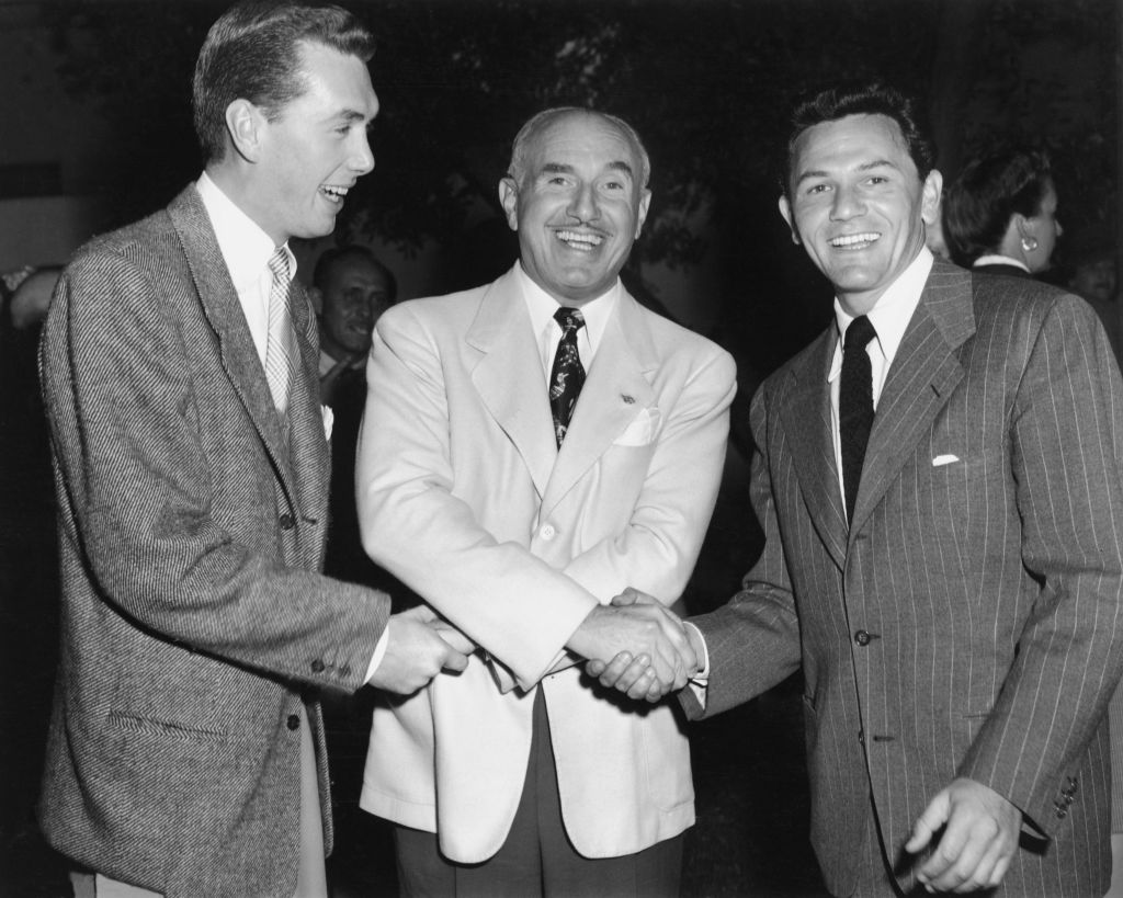 Jack Warner (1892 - 1978, centre) in a three-way handshake