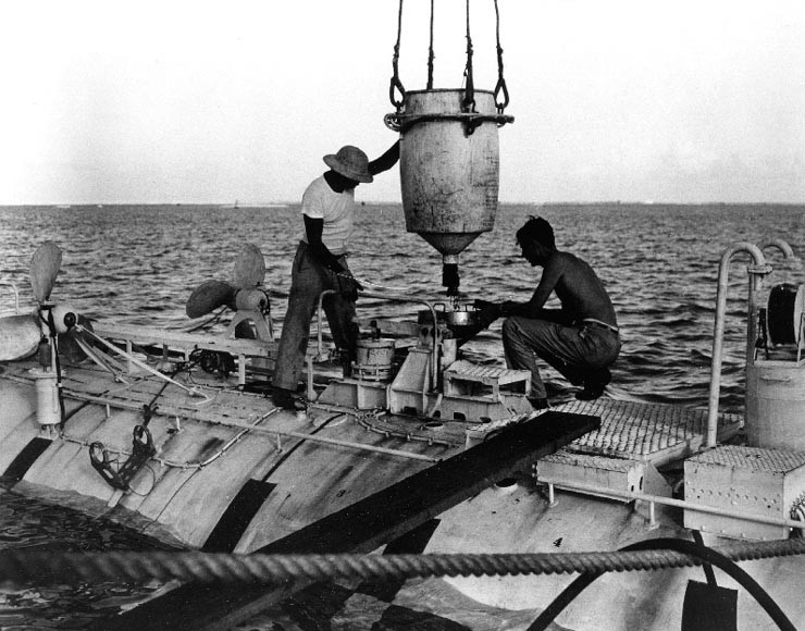 Jacques Piccard (right), co-designer of the bathyscaphe, and Ernest Virgil loading iron shot ballast into Trieste, prior to her record 18,600 foot descent in in the Marianas Trench
