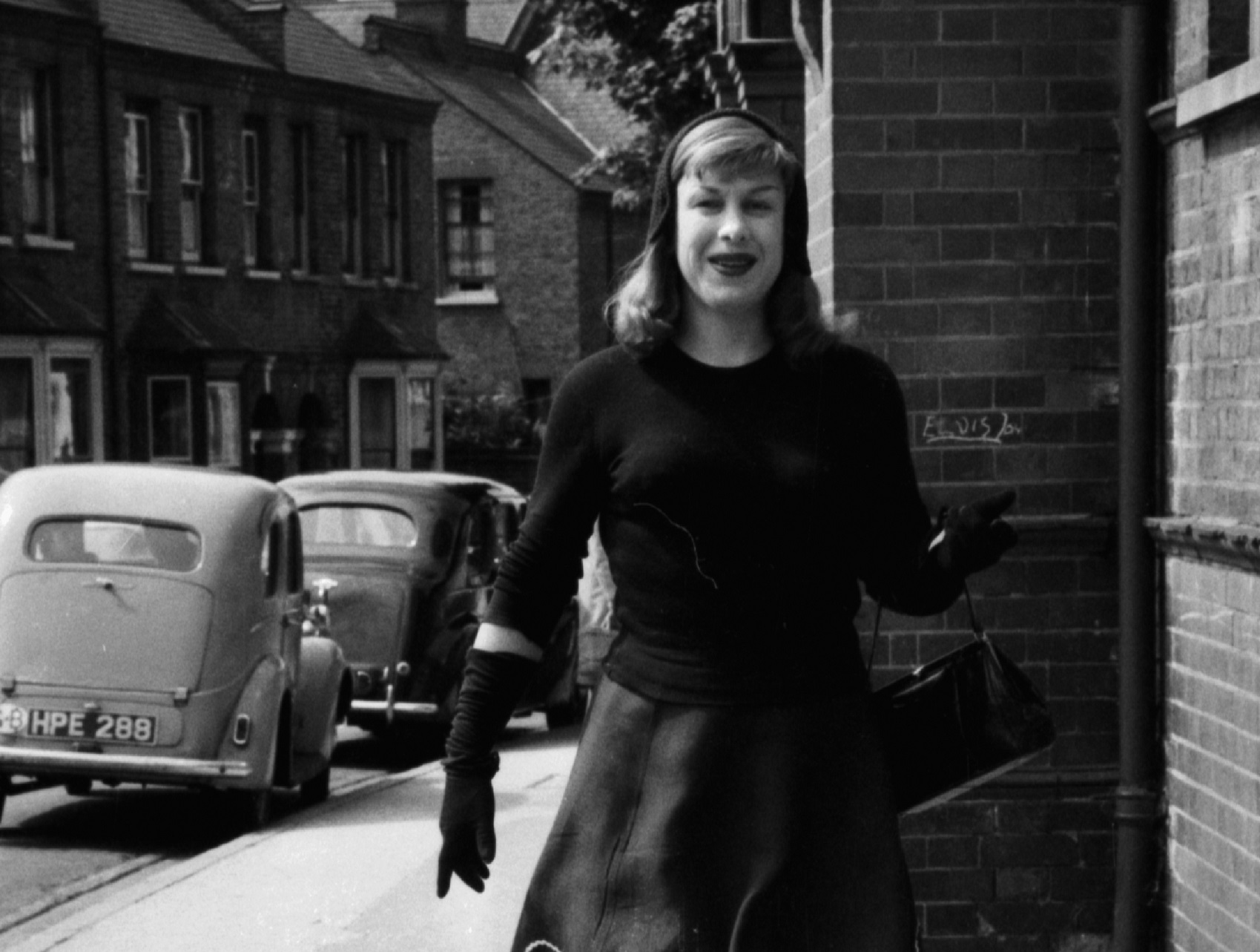 Roberta Cowell walking down a street, 1958. Cowell, a former racing driver and RAF pilot