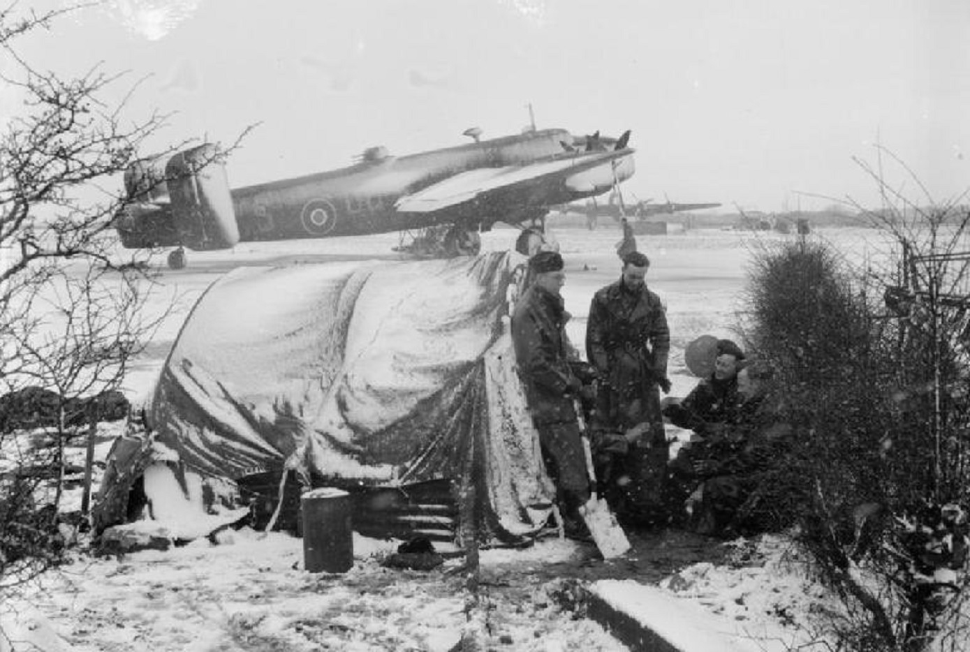Ground crew warm themselves on a stove in the snow - 1942/45