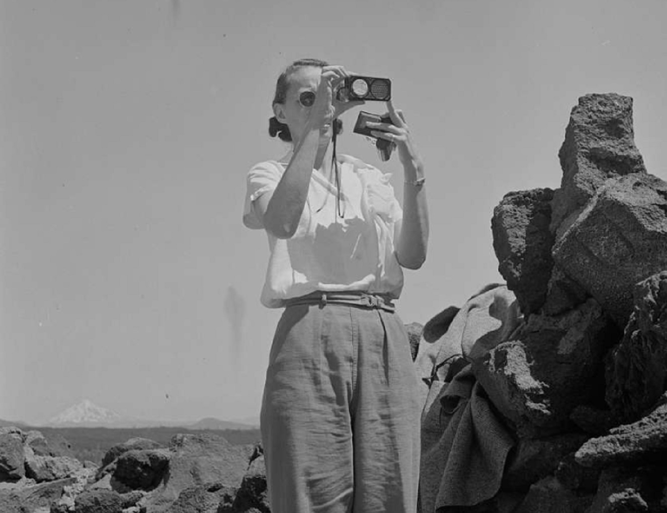 A black and white photo of a woman taking a picture - 1942