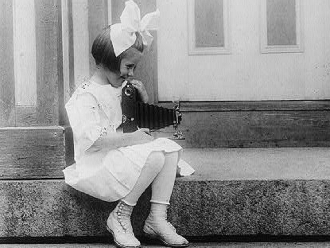 Young girl taking a Kodak picture of her doll - 1917