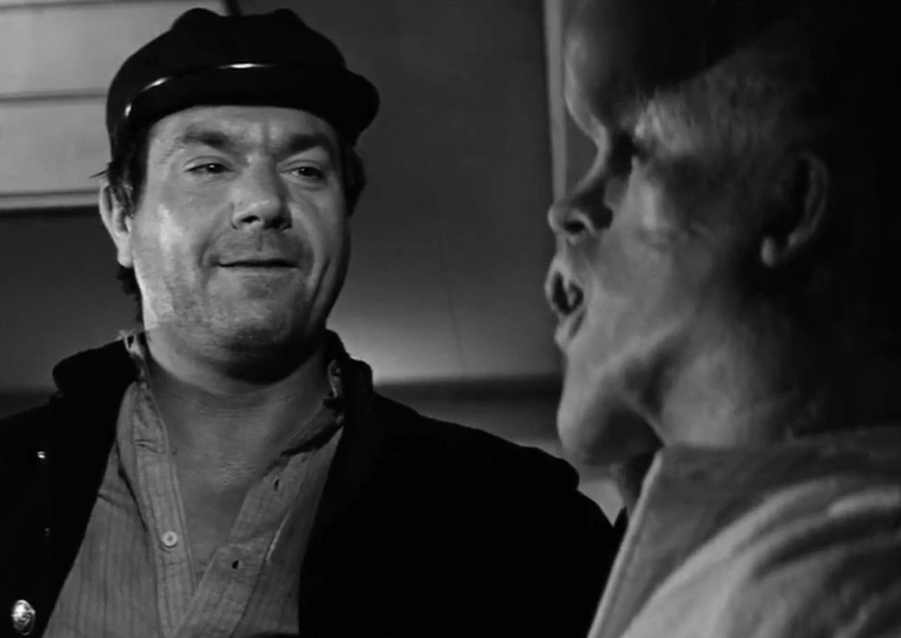 B&W Screenshot of Joseph Merrick (John Hurt) looking at side and talking with other man - from Elephant Man (1980)