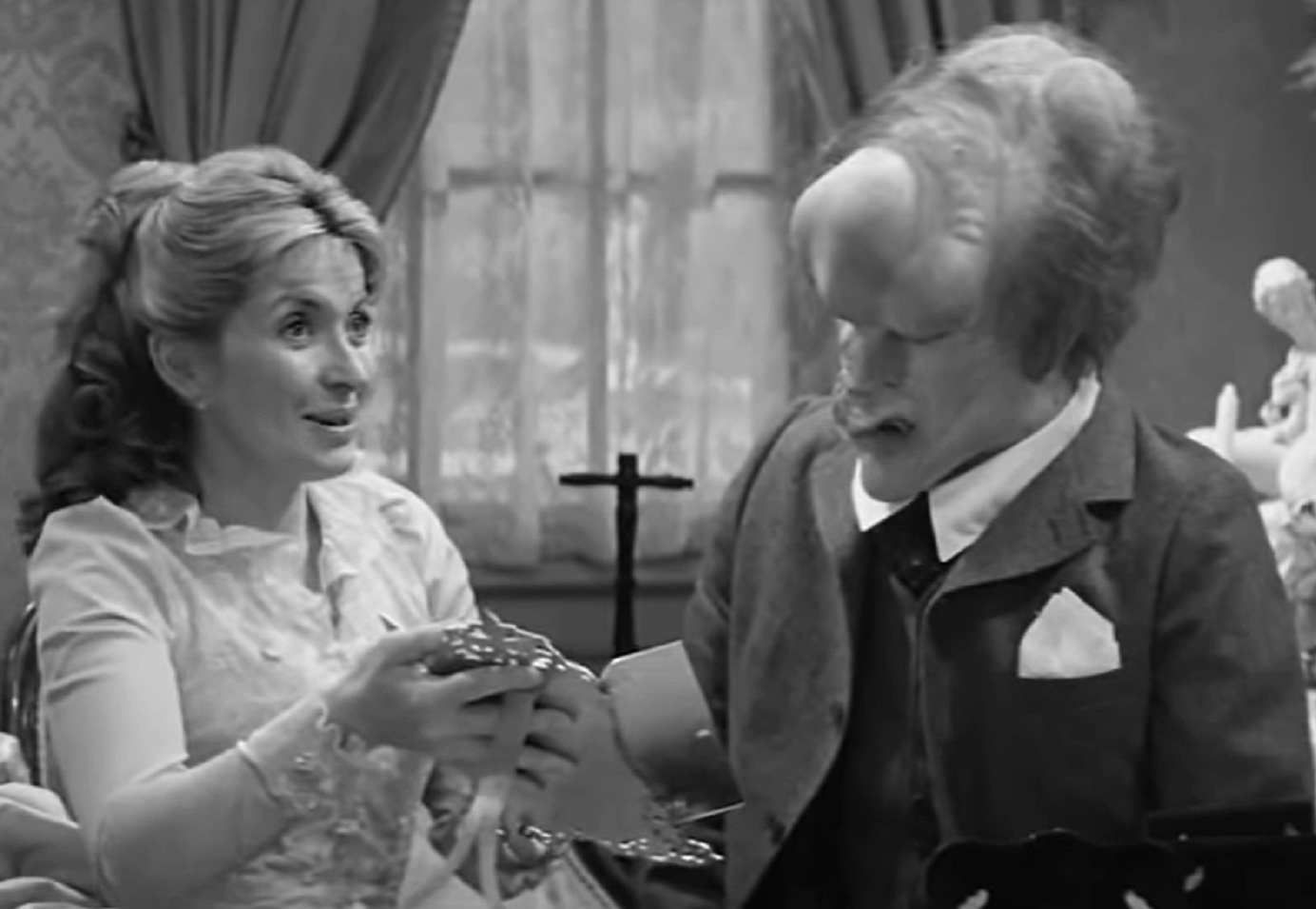 B&W Screenshot of Joseph Merrick (John Hurt) looking at female standing next to him - from Elephant Man (1980)