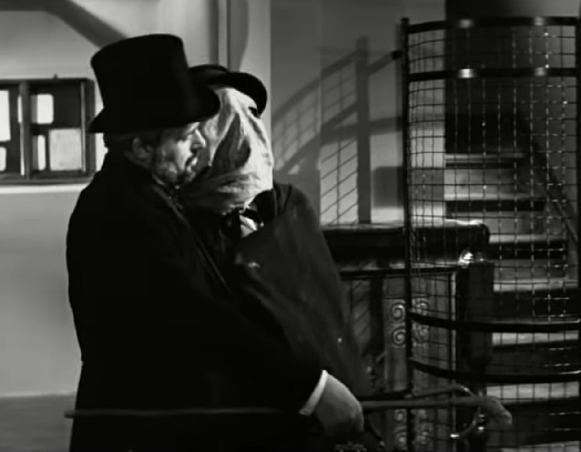 B&W Screenshot of Joseph Merrick (John Hurt) walking in hospital with covered face - from Elephant Man (1980)