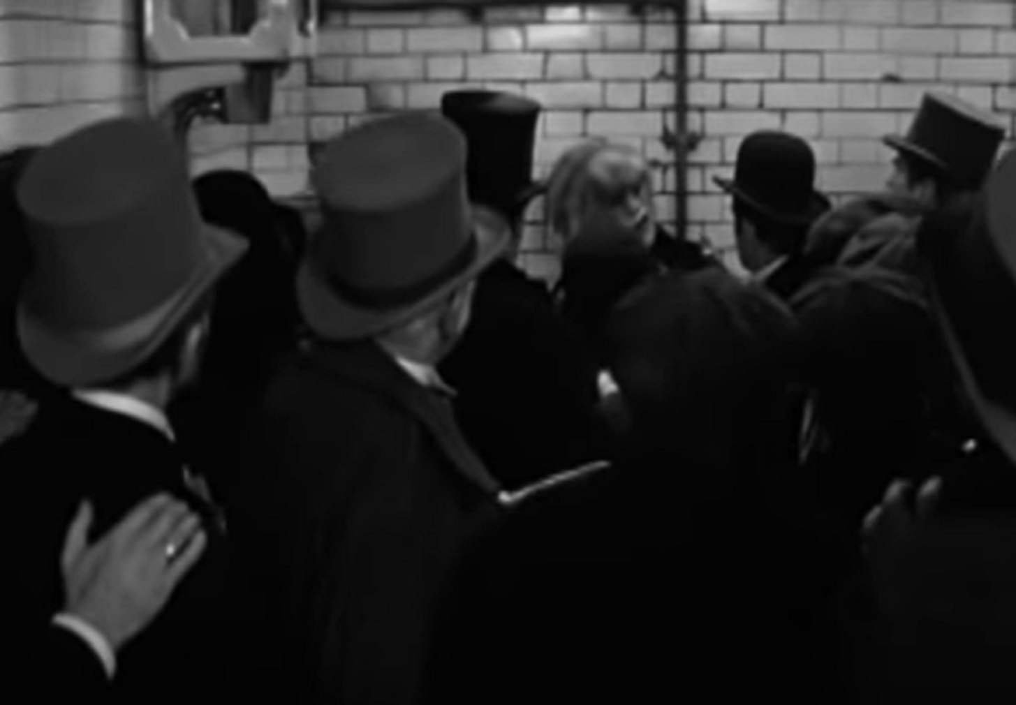 B&W Screenshot of Joseph Merrick (John Hurt) standing in front of people at train station - from Elephant Man (1980)