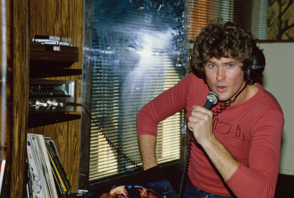 American actor and singer David Hasselhoff, wearing a red long-sleeve t-shirt as he holds a microphone