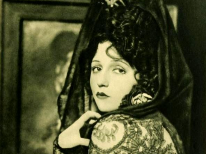 Portrait of the Actress Bebe Daniels wearing a floral pattern dress and a glamorous black hat