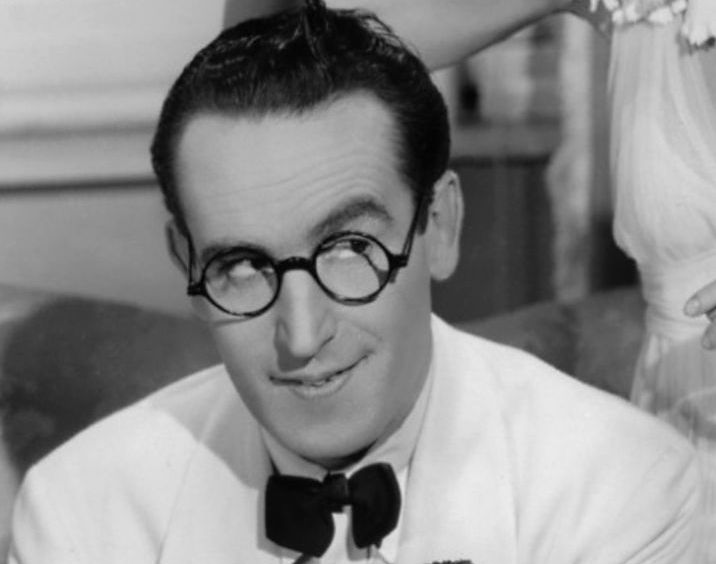 Actor Harold Lloyd in The Movie The Milky Way wearing a white suit with black tie and smiling