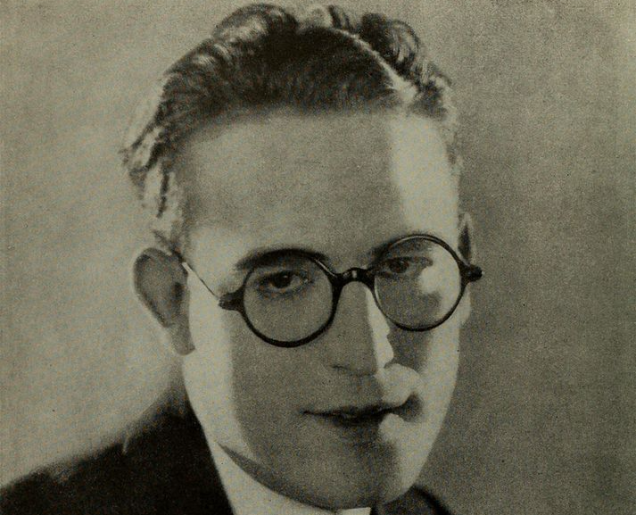 Grayscale Portrait Photo of American actor Harold Lloyd wearing a gray suit and smiling facing the camera