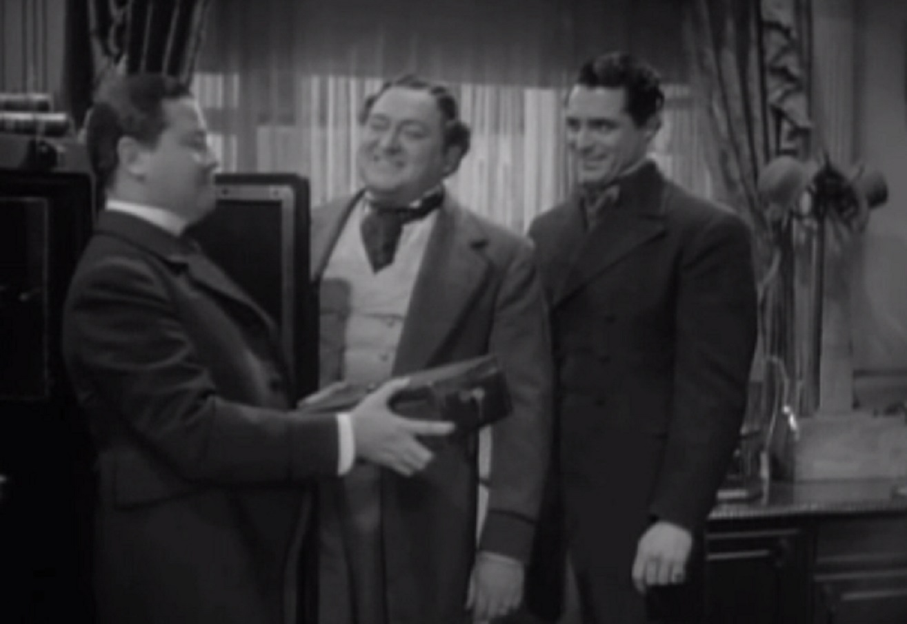 Screenshot of James Fisk (Edward Arnold) giving a box from safe to other man - from The Toast of New York (1937)