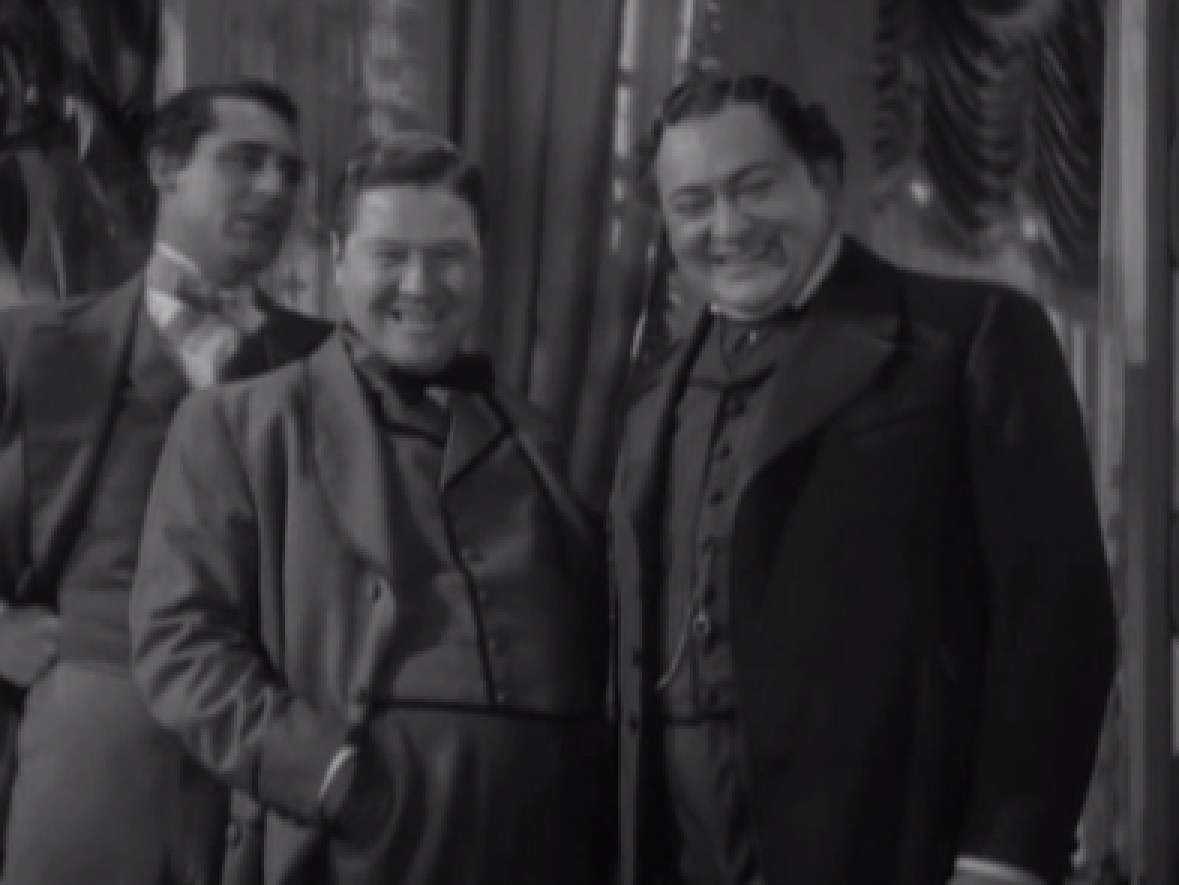 Screenshot of James Fisk (Edward Arnold) wearing suit and smiling with other people people- from The Toast of New York (1937)