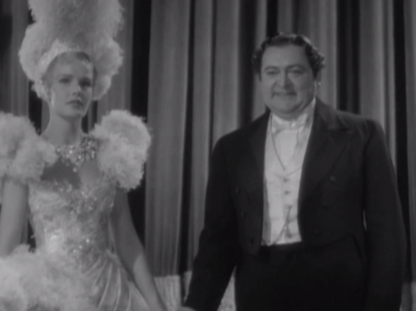 Screenshot of James Fisk (Edward Arnold) and Fleurique (Thelma Leeds) standing and looking in camera - from The Toast of New York (1937)