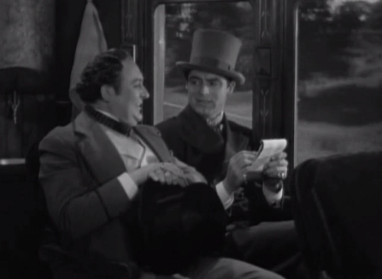 Screenshot of James Fisk (Edward Arnold) seating and talking with other man in train- from The Toast of New York (1937)