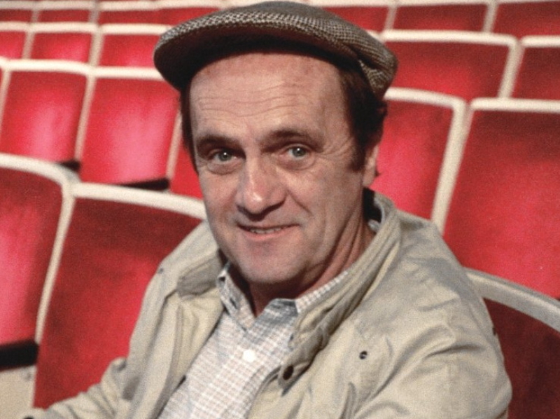 Bob Newhart in beige jacket and a hat