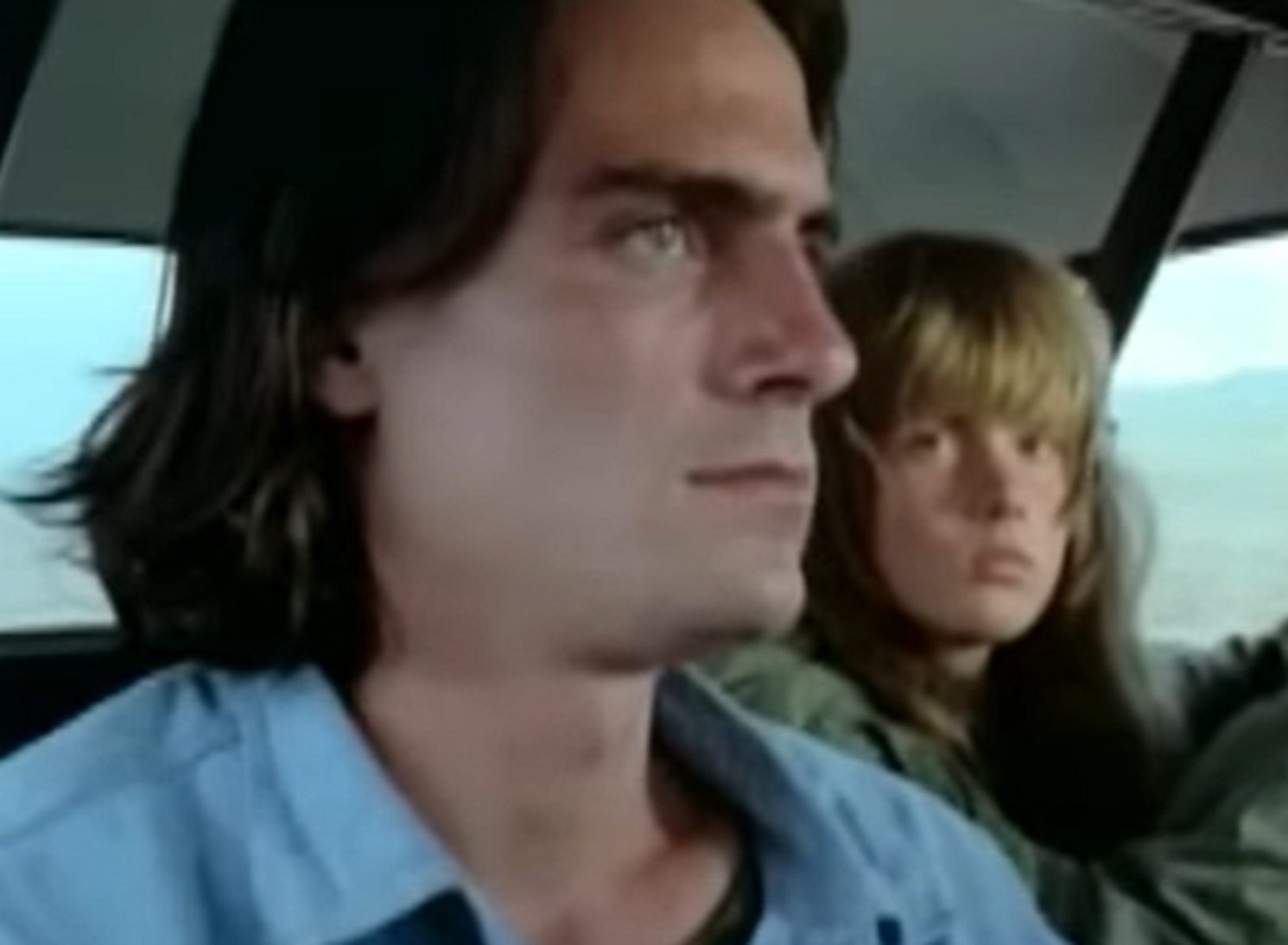 Screenshot of James Taylor with long hair is driving a car with other female - from Two-Lane Blacktop (1971)