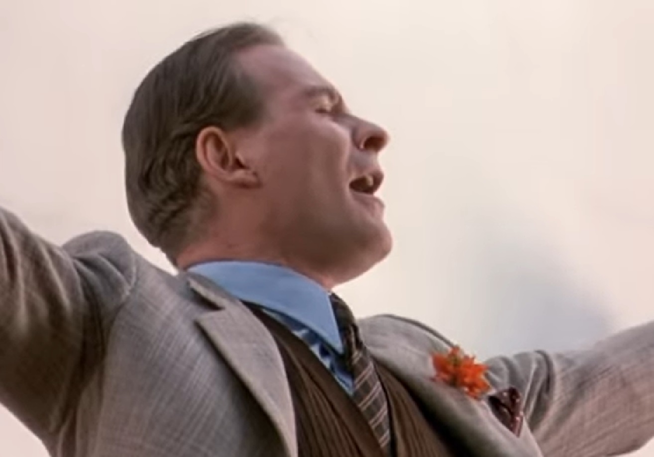Screenshot of Cole Porter (Kevin Kline) wearing suit is singing outside from - De-Lovely (2004)