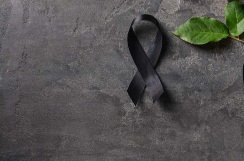 Black mourning ribbon, flowers and candle