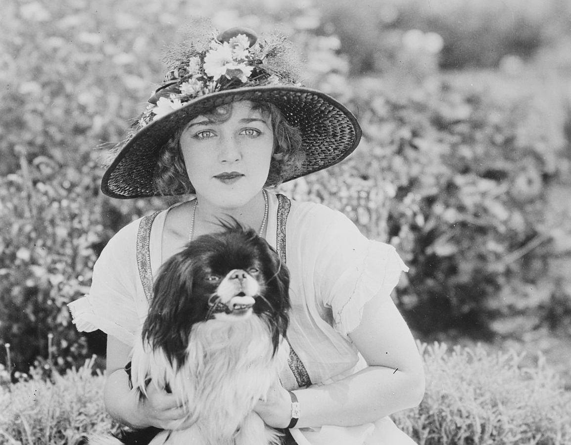B&W photo of Mildred Davis holding a dog in her hands ,looking at camera - 1921