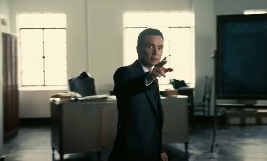 Cillian Murphy as Robert Oppenheimer with hand in front talking to someone in suit