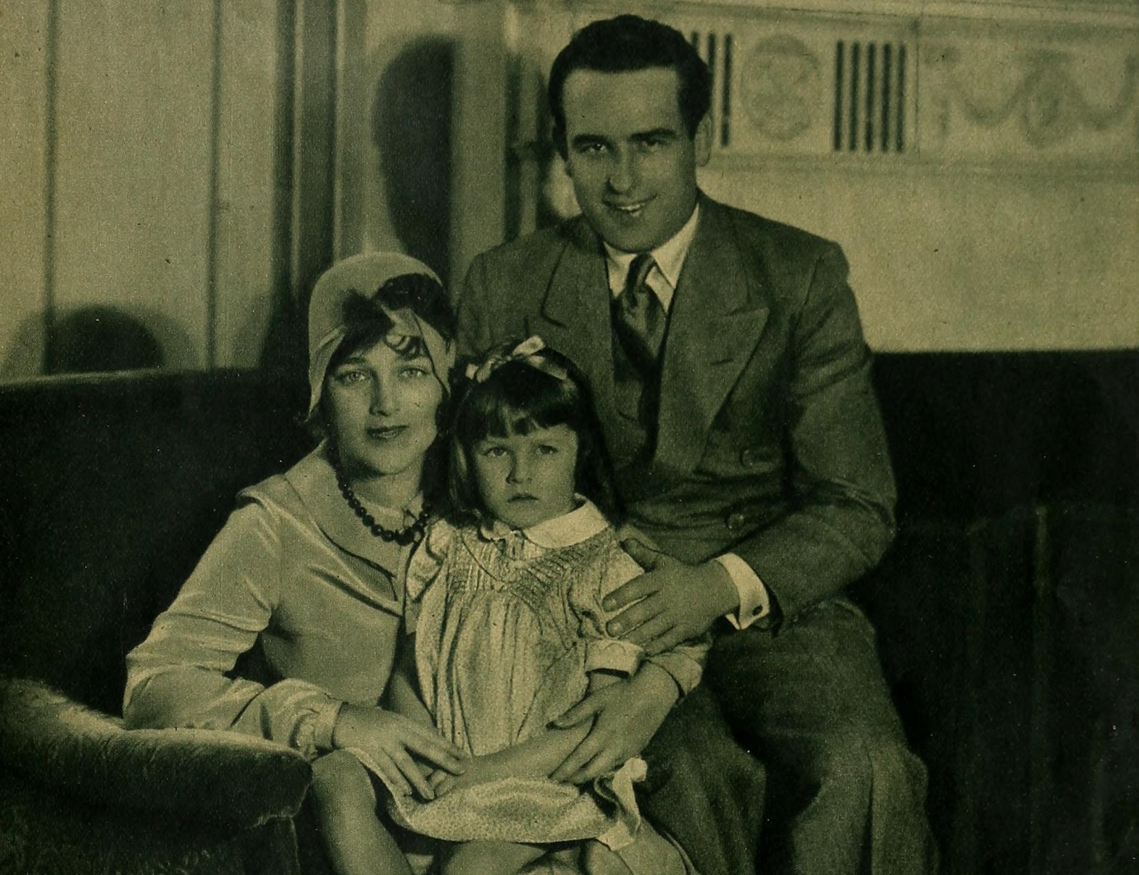Harold, Mildred, and Gloria Lloyd seating on the sofa in the house and looking at camera - 1929