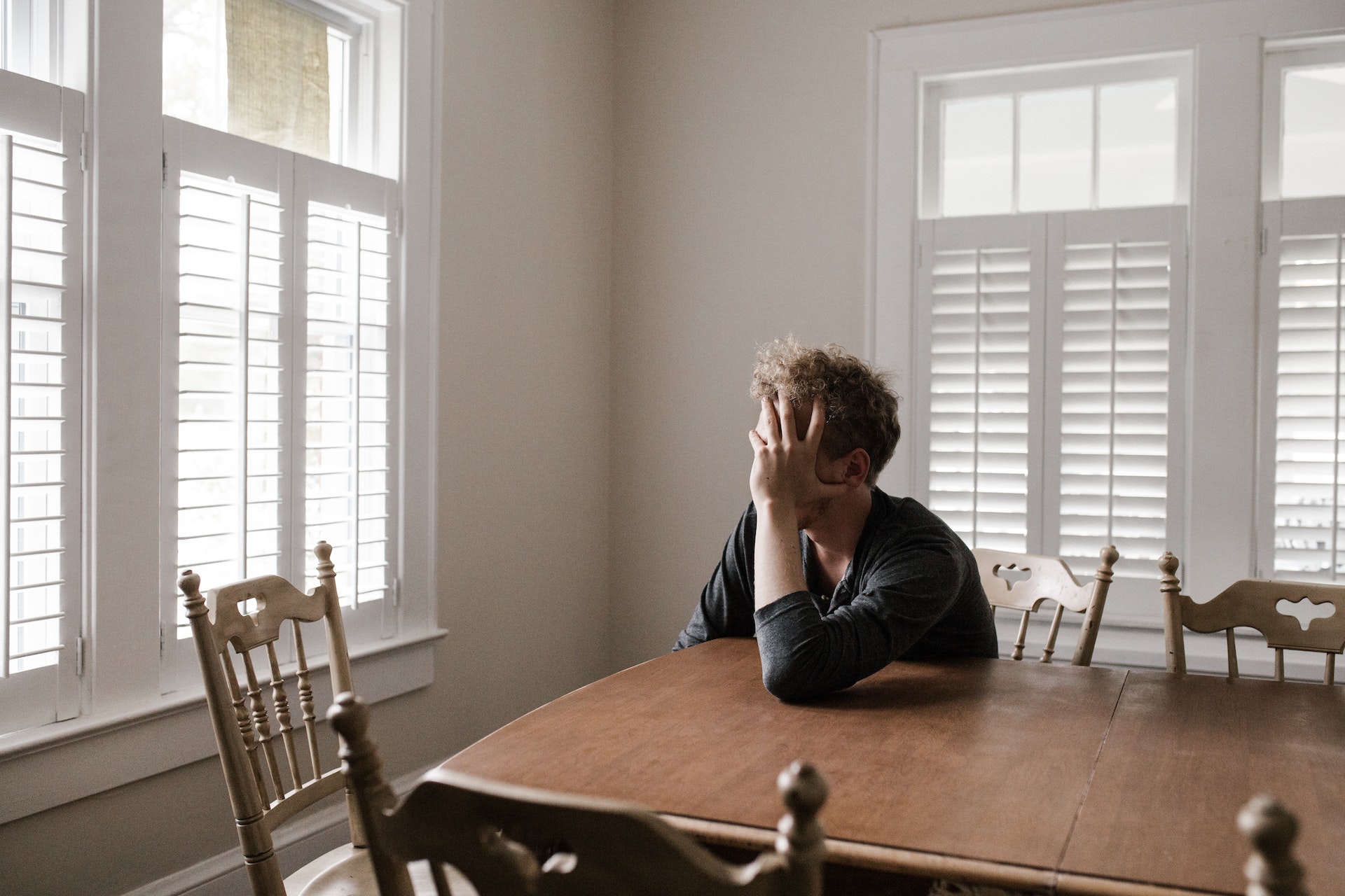 Lonely man sitting on a kitchen table in a gray sweatshirt
