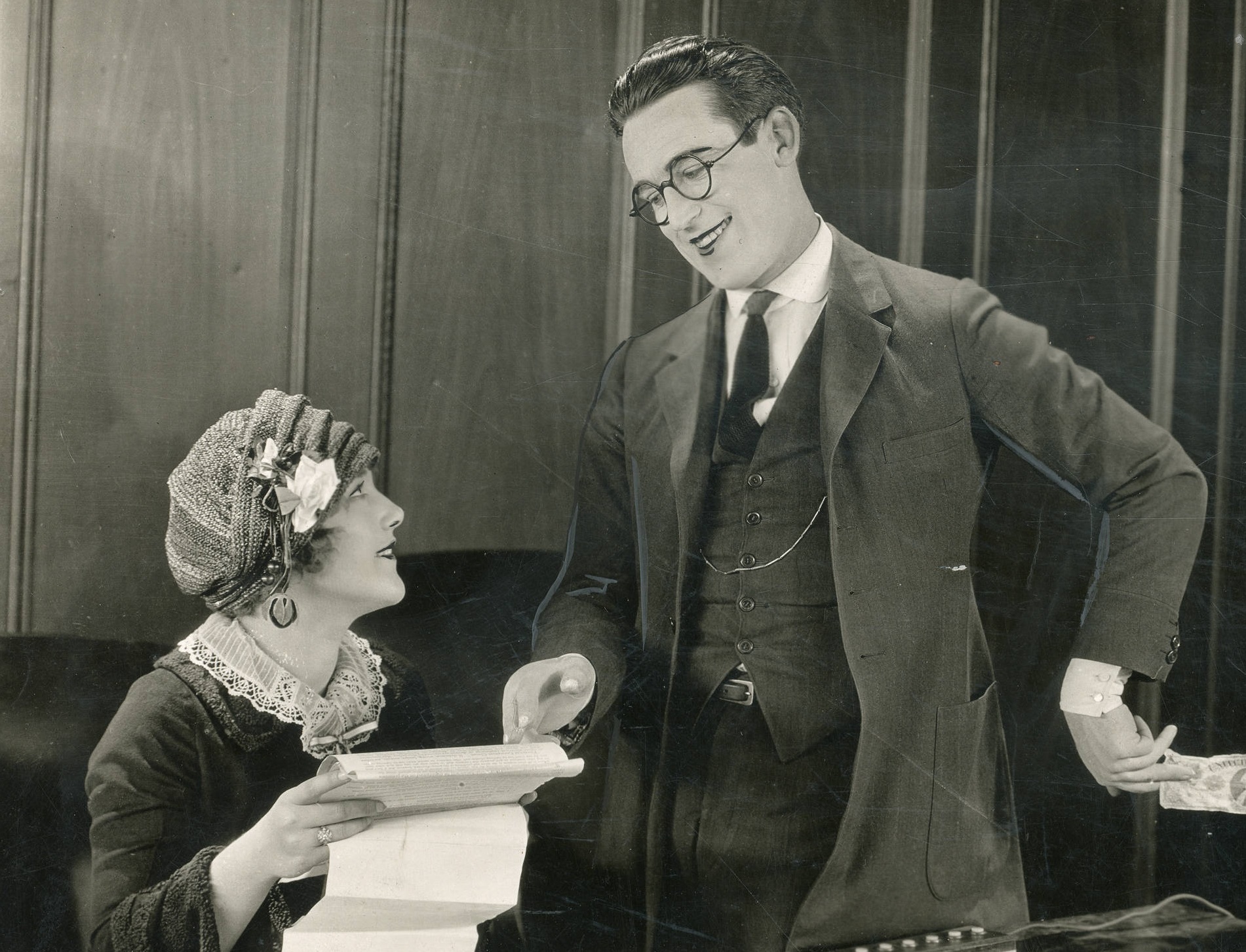 Photo of Harold Lloyd smiling and Mildred Davis holding a paper and looking at him - Still from the American comedy film Safety Last! (1923).