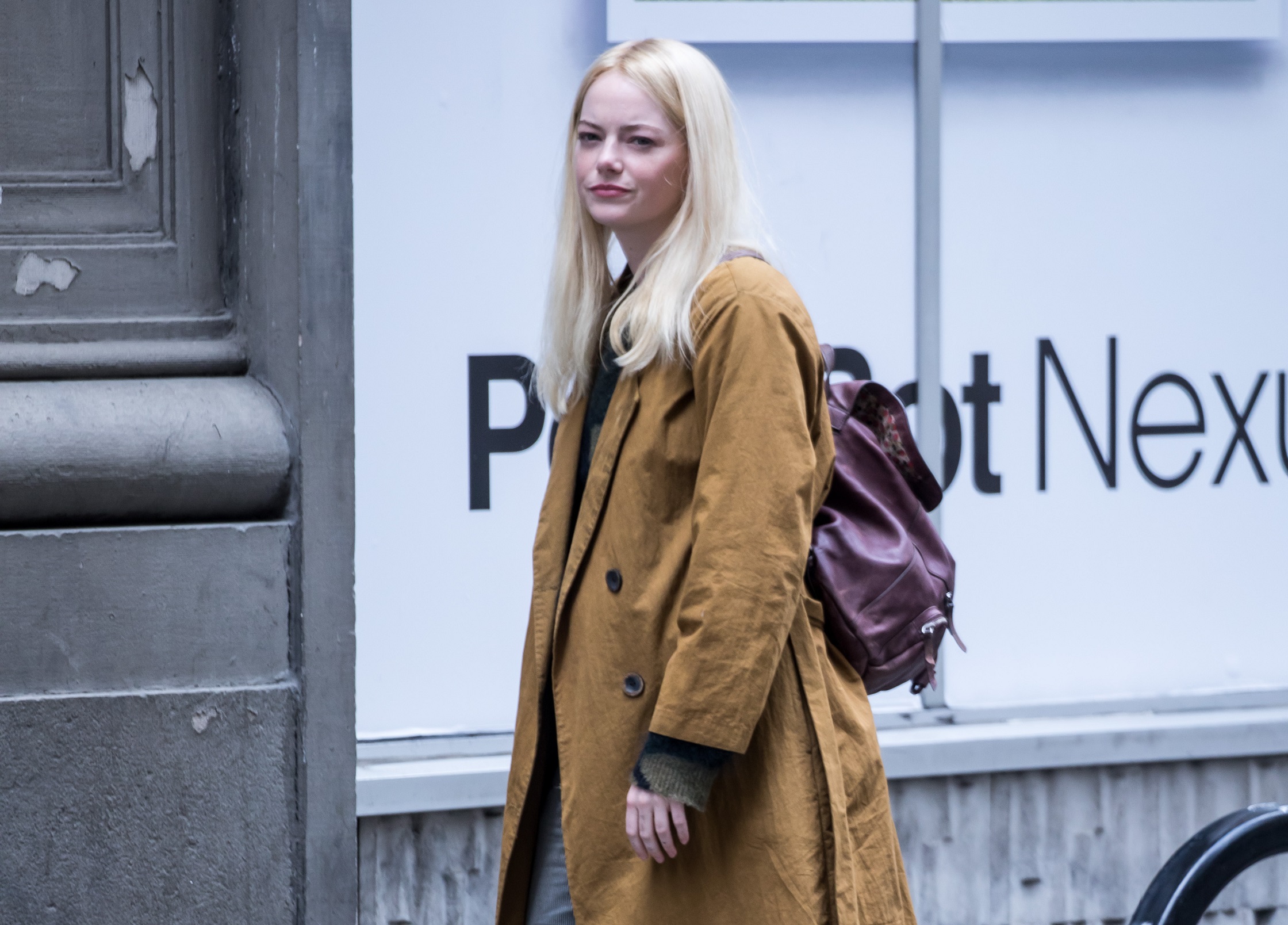 Emma Stone wearing orange coat and purple backpack on the street - 2018