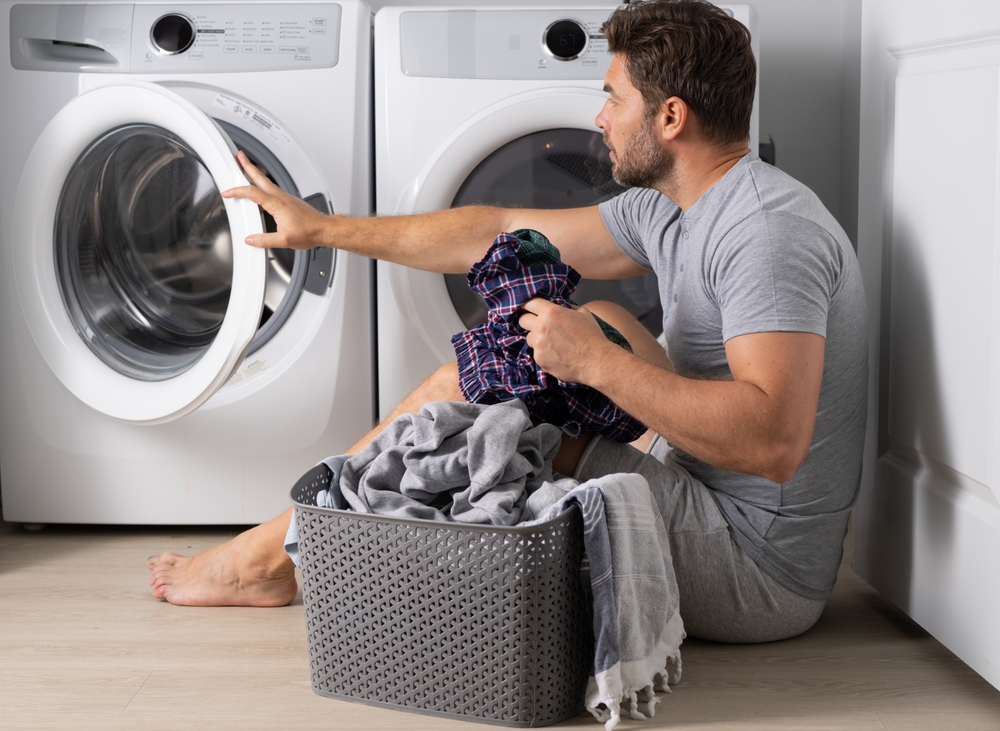 A handsome man sits in front of a washing machine