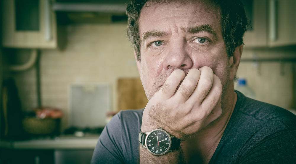 Sad man sitting on a kitchen chair in gray t-shirt