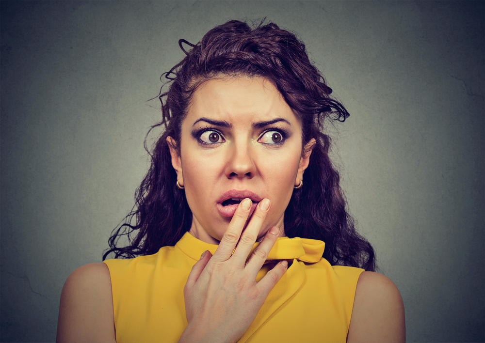 Scared shocked woman isolated on gray background in yellow blouse