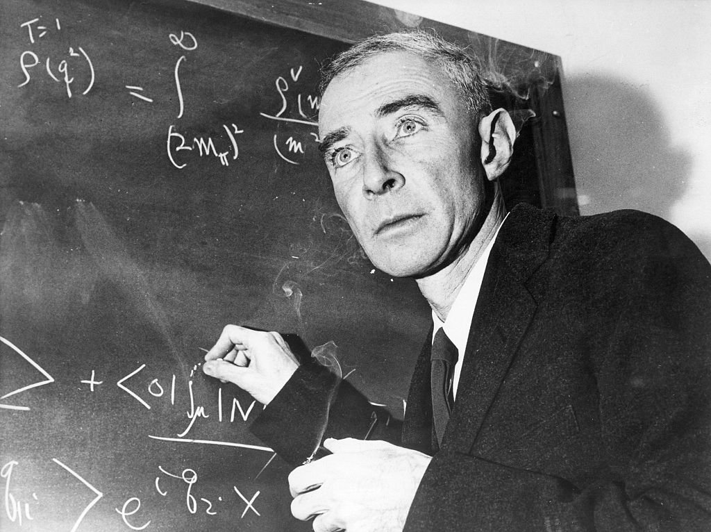 Robert Oppenheimer in suit solving mat problems