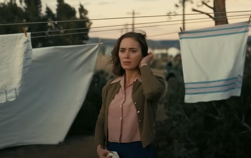 Emily Blunt as Kitty Oppenheimer  outside surrounded  by sheets in green sweater