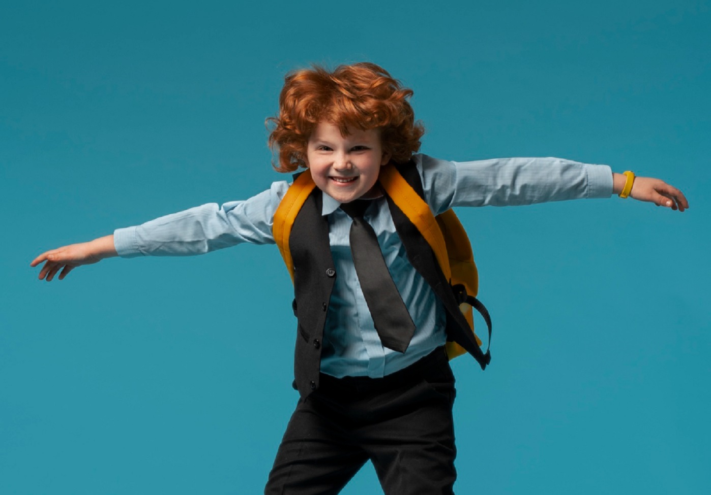 Kid jumping with open hands on a blue background.