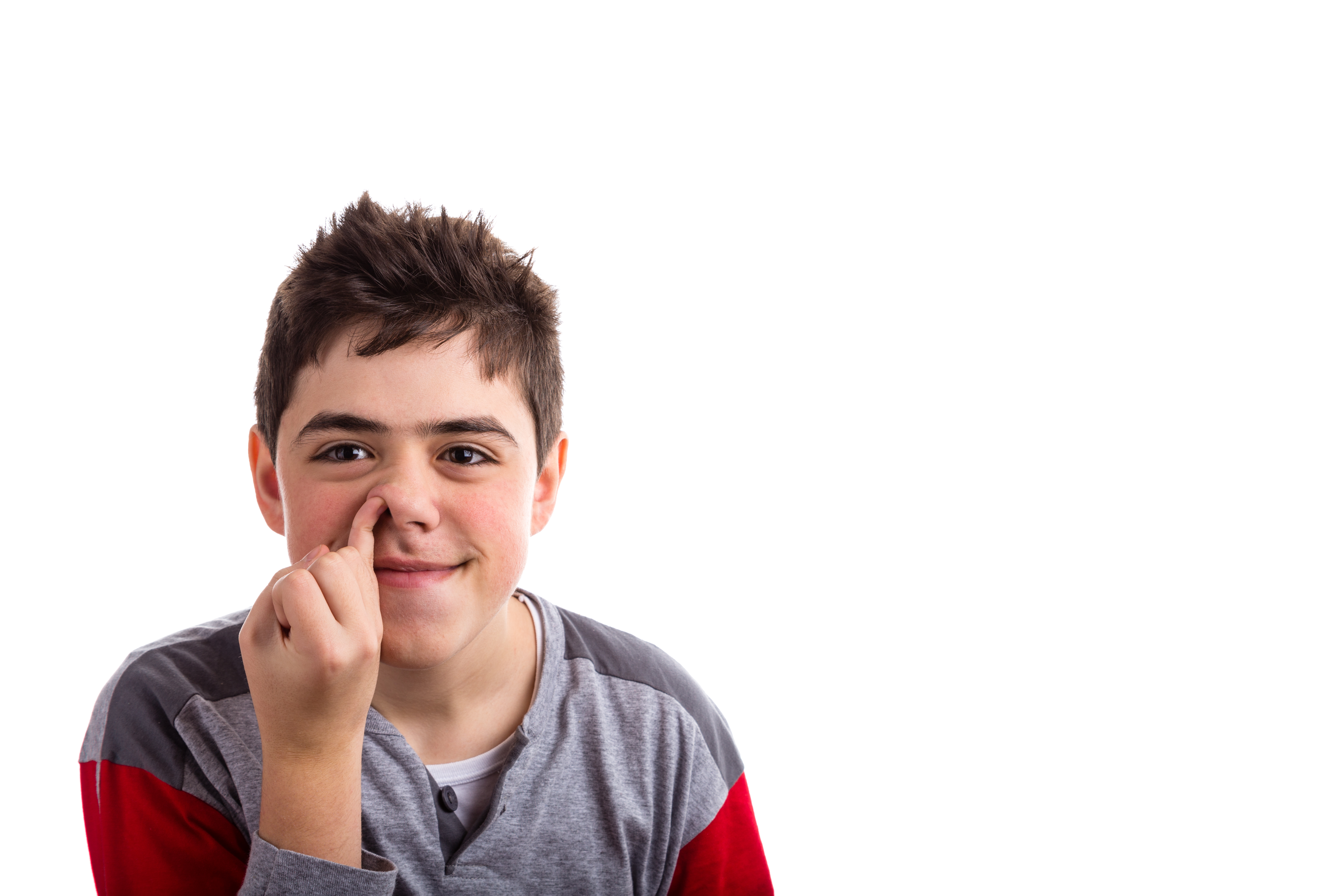 Caucasian boy smiles and putting pinkie finger in his nose.