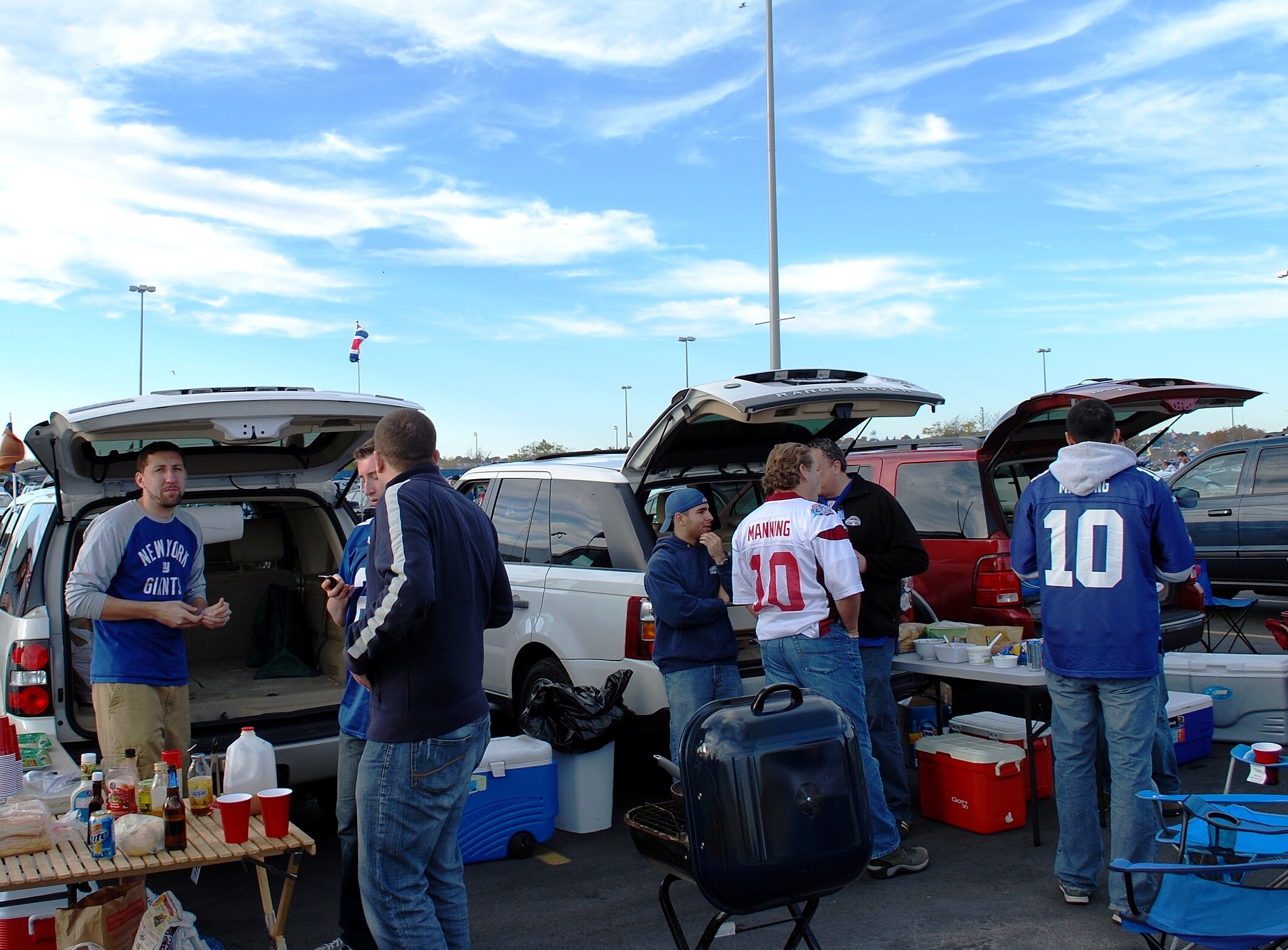 People are standing outside and having a tailgate party.