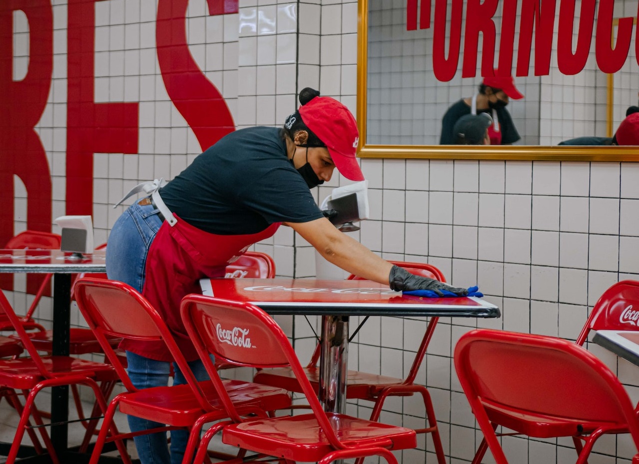 Woman working at restaurant is cleaning the table.