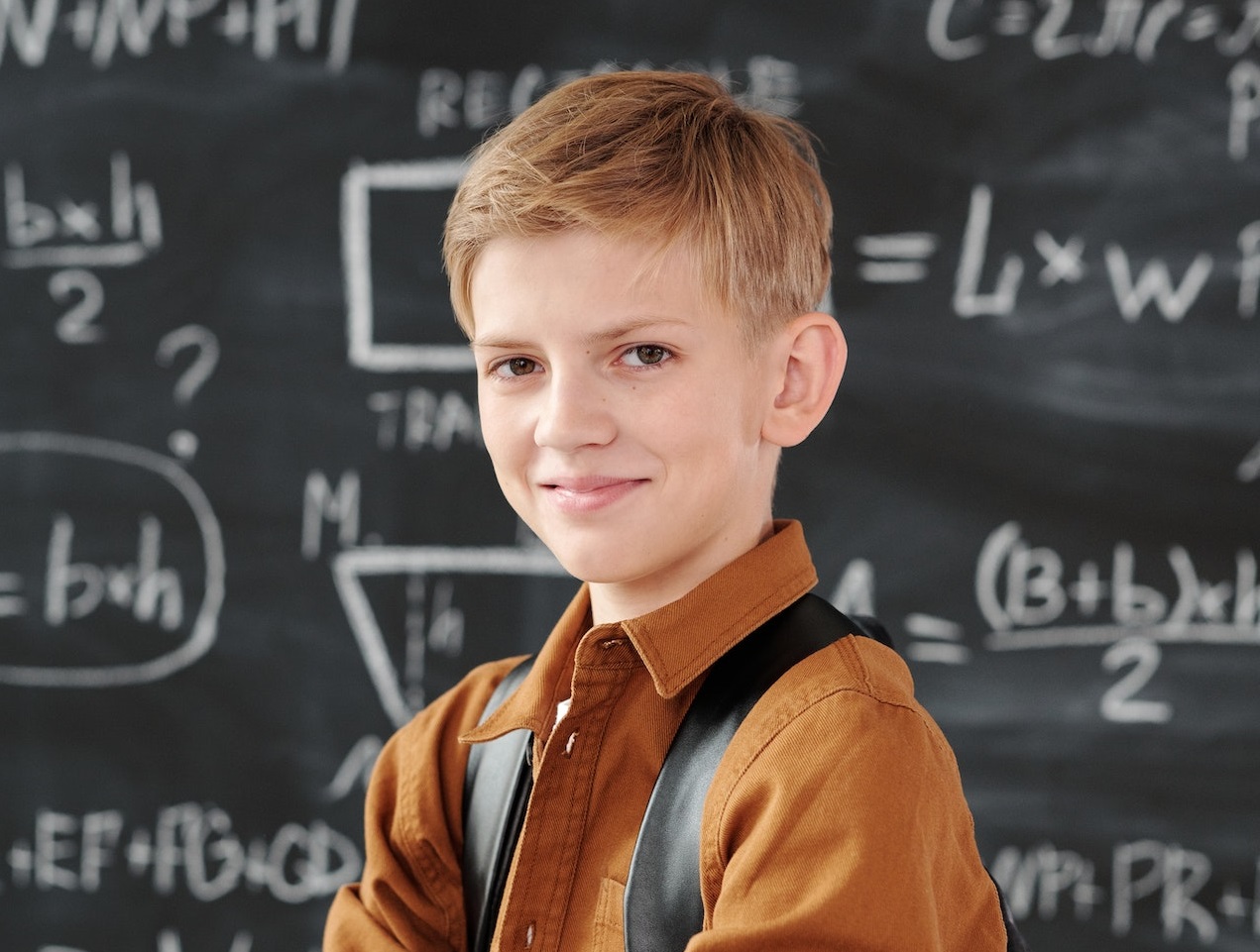 Kid looking at camera and smiling in classroom.