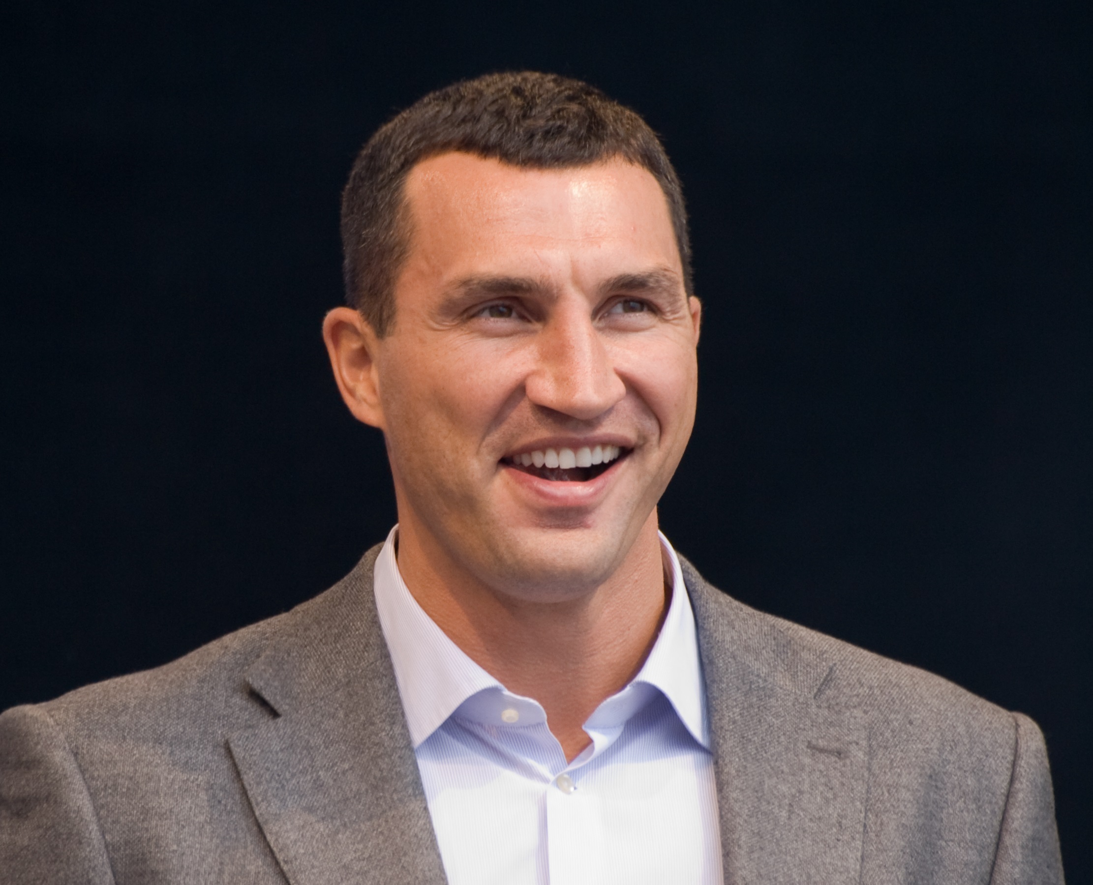 Wladimir Klitschko wearing grey suit and white shirt looking at side and smiling - 2012.