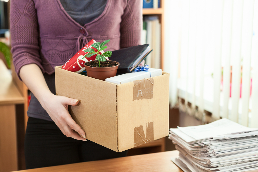 Office white collar worker with things collected in a box leaving the office after being fired