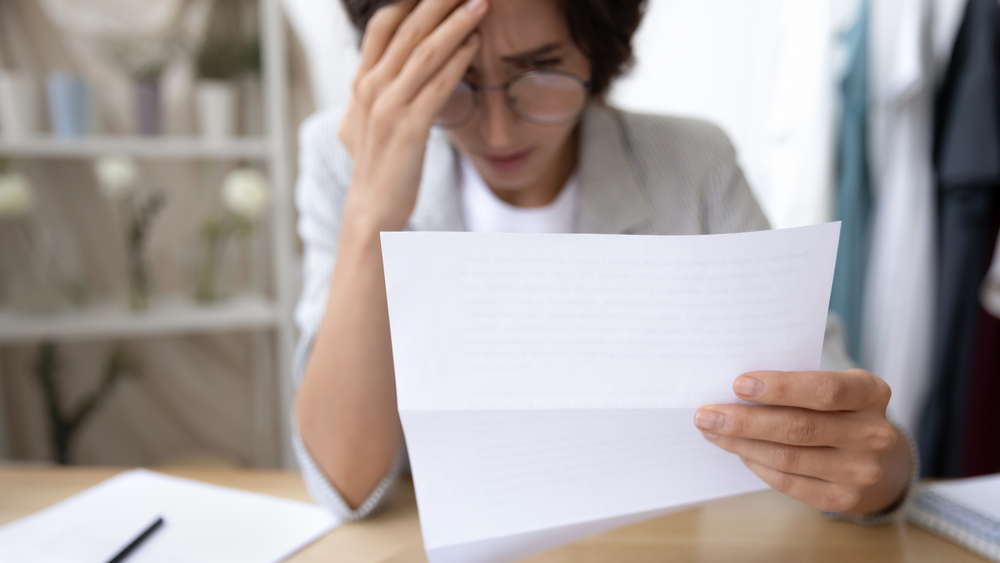 Shocked woman with glasses reading a letter of job termination