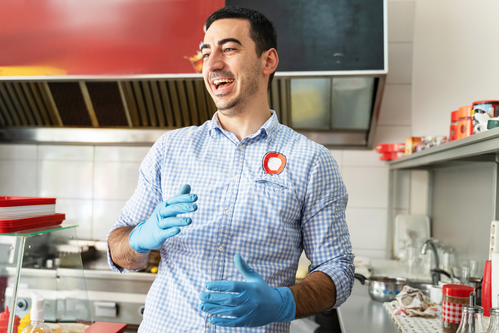 Male fast food employee in plaid blue shirt laughing